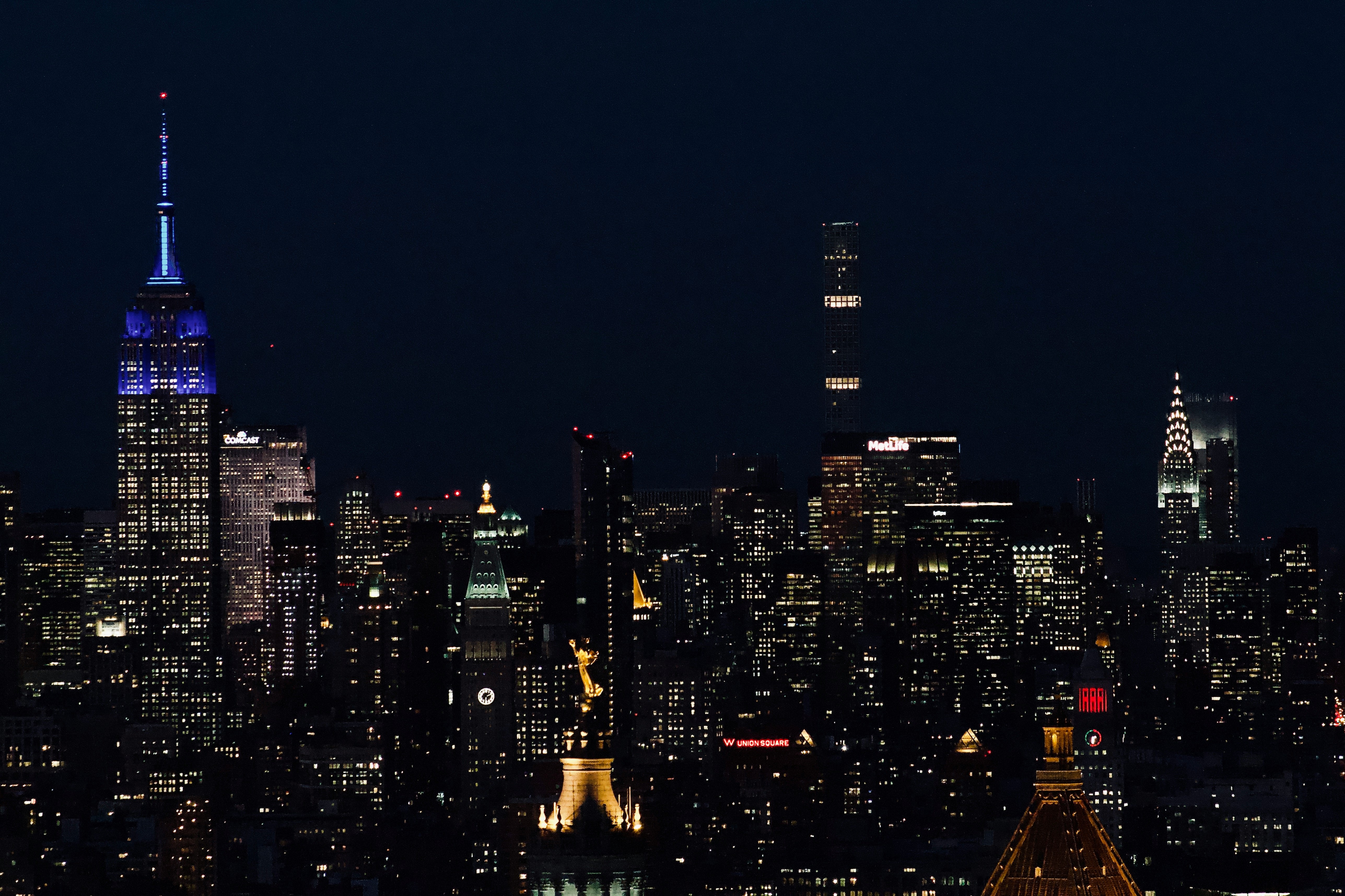 Empire State Building lit up at night above midtown Manhattan
